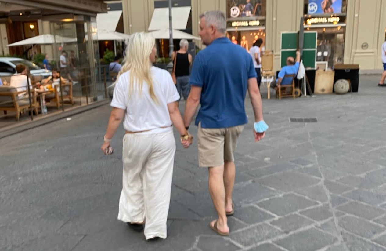 Couple walking hand-in-hand past Hotel Savoy in Florence’s Piazza della Repubblica