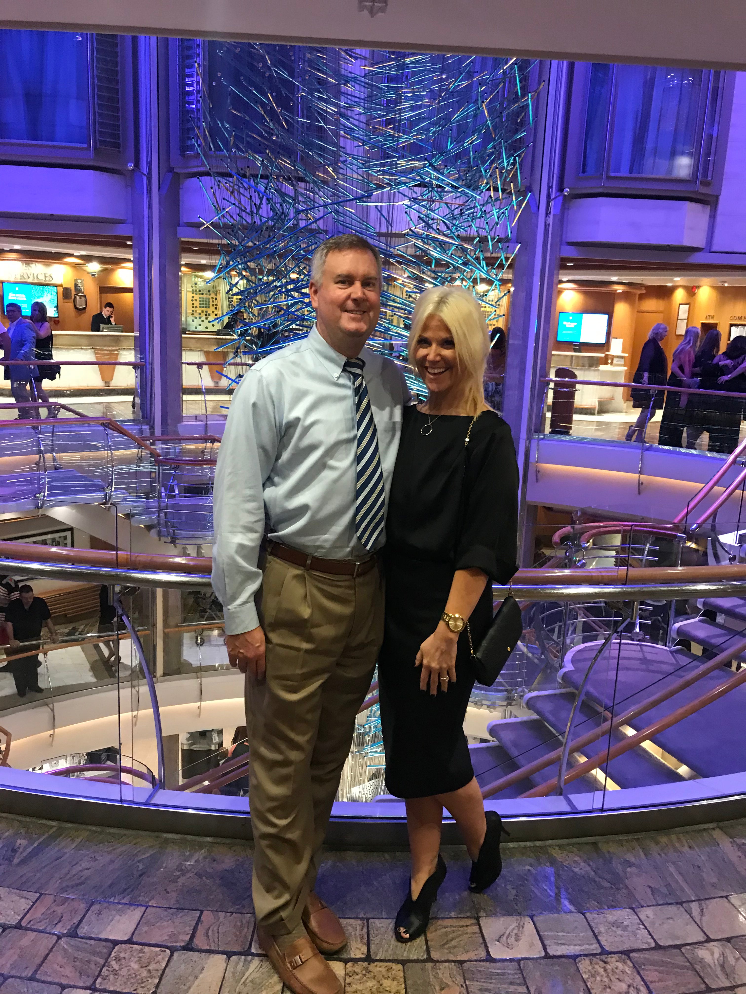 Couple dressed for dinner standing in the cruise ship atrium after changing out of casual beachwear,